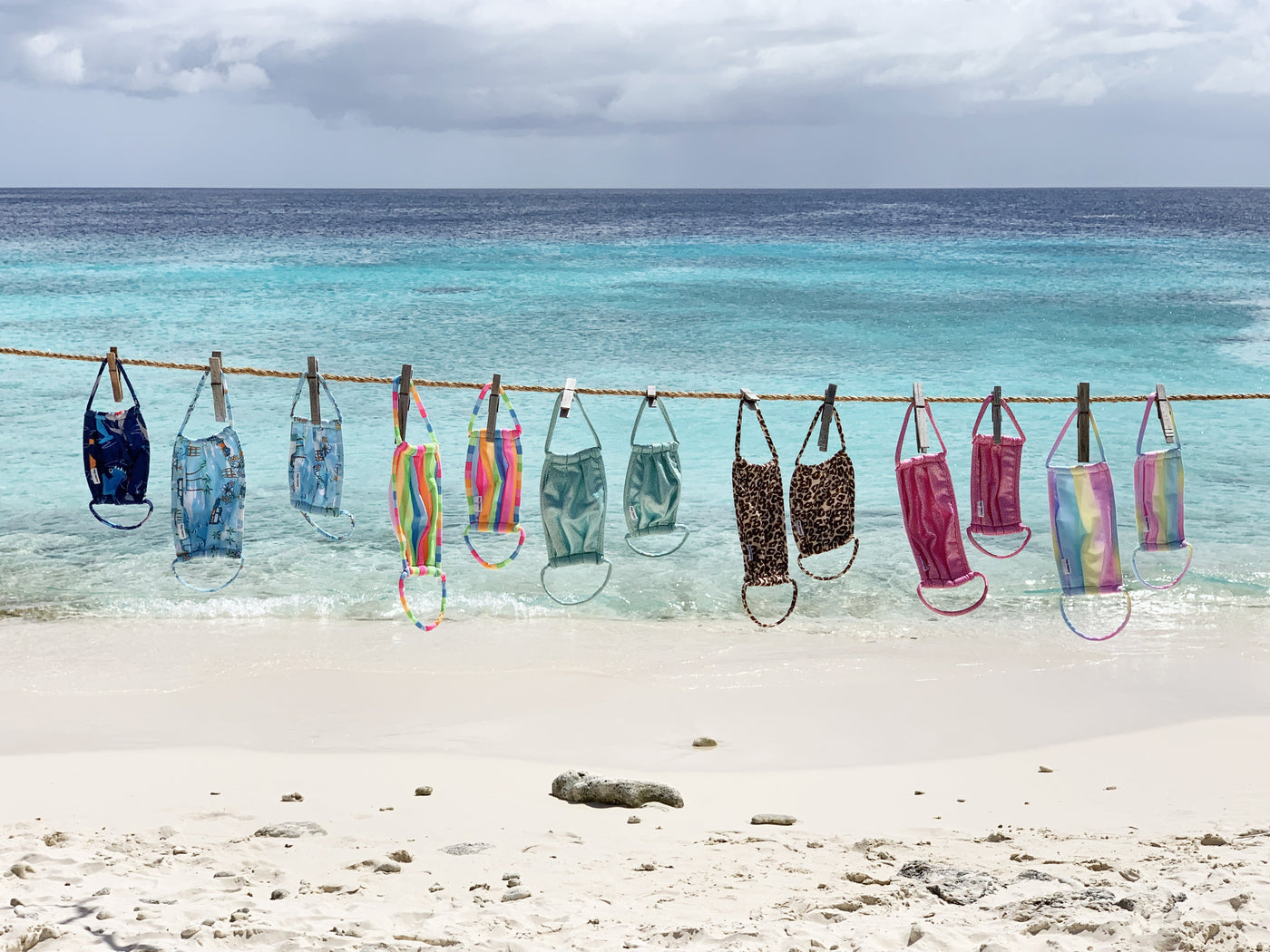 Clothing line at the beach with hanging face masks of various colors from the Flap Happy face masks collection.